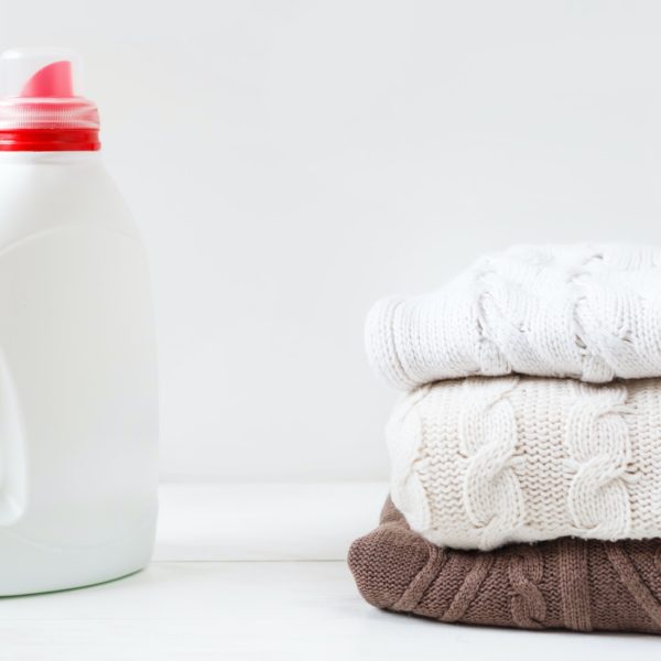 White bottle with liquid detergent and laundered flesh colored soft pullovers.